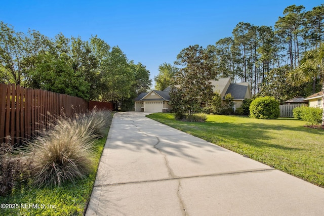 view of front facade featuring driveway, an attached garage, fence, and a front lawn