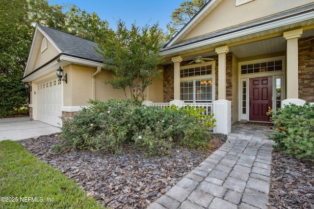 entrance to property with stone siding, an attached garage, concrete driveway, stucco siding, and covered porch