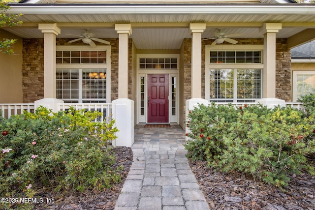 entrance to property with ceiling fan, a porch, and stone siding