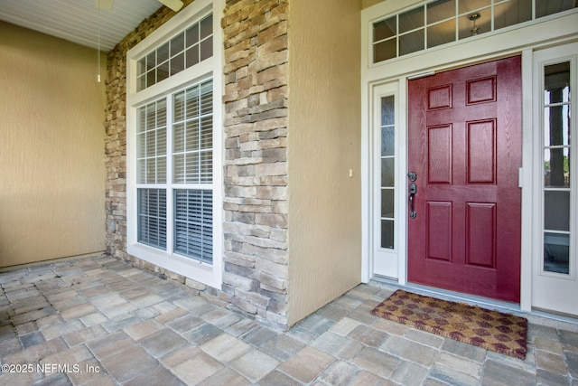 entrance to property featuring stone siding and covered porch