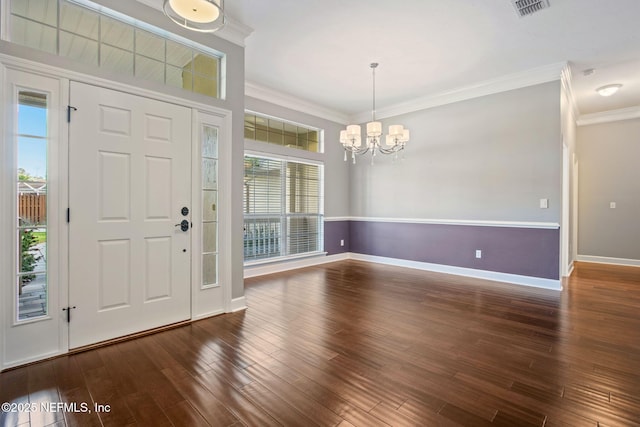 foyer entrance featuring visible vents, crown molding, baseboards, wood finished floors, and an inviting chandelier