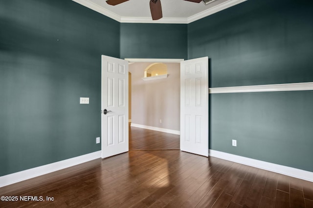 empty room with wood finished floors, ornamental molding, baseboards, and ceiling fan