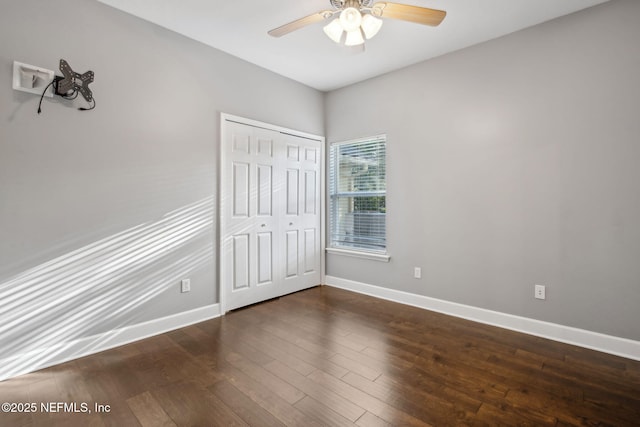 unfurnished bedroom featuring dark wood finished floors, baseboards, a closet, and a ceiling fan
