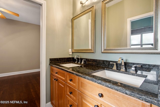 bathroom with baseboards, double vanity, a sink, and a ceiling fan