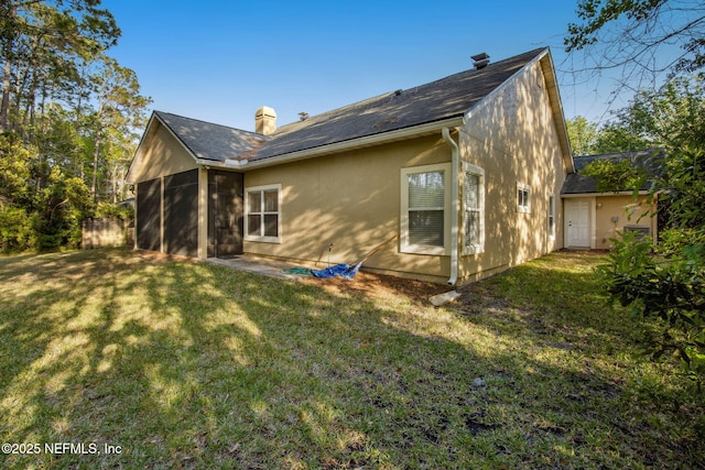 rear view of property featuring a chimney and a yard