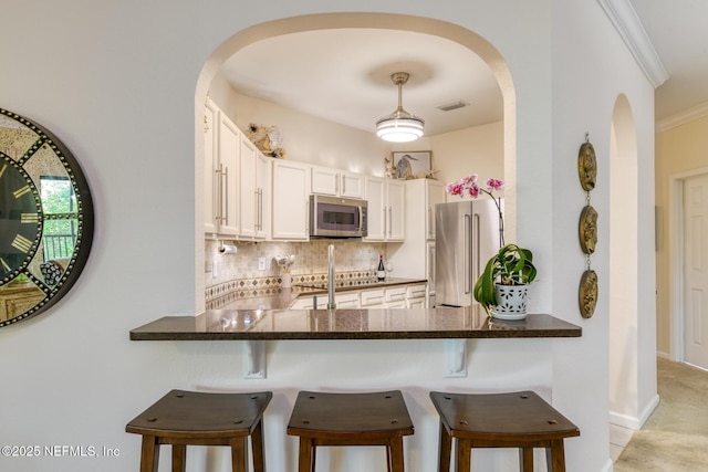 1825 Vista Cove Rd, Saint Augustine, FL 32084 - kitchen with stainless steel appliances, arched walkways, a peninsula, and crown molding