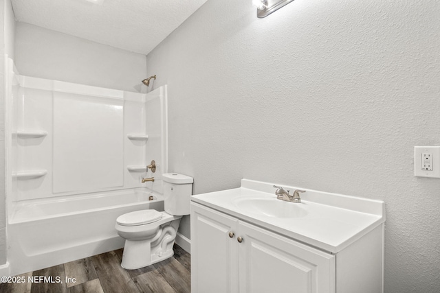 bathroom with toilet, vanity, wood finished floors, a textured ceiling, and a textured wall