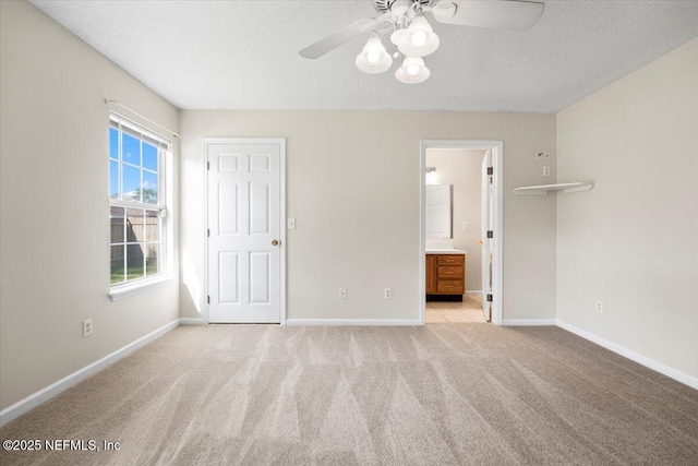 unfurnished bedroom featuring light carpet, a textured ceiling, and baseboards