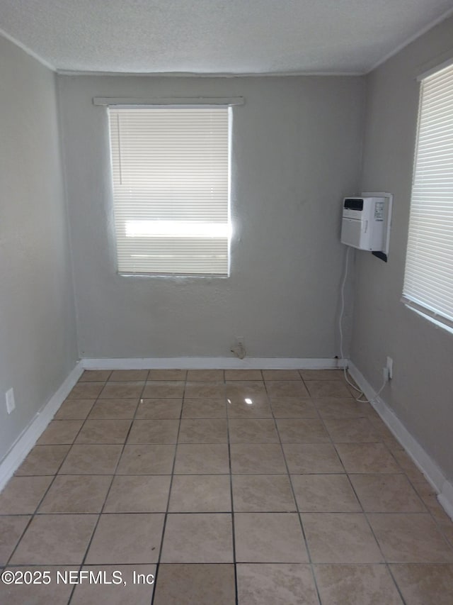 1419 Brady St Unit 1-2, Jacksonville, FL 32209 - spare room featuring light tile patterned floors, baseboards, a wall mounted air conditioner, and a textured ceiling