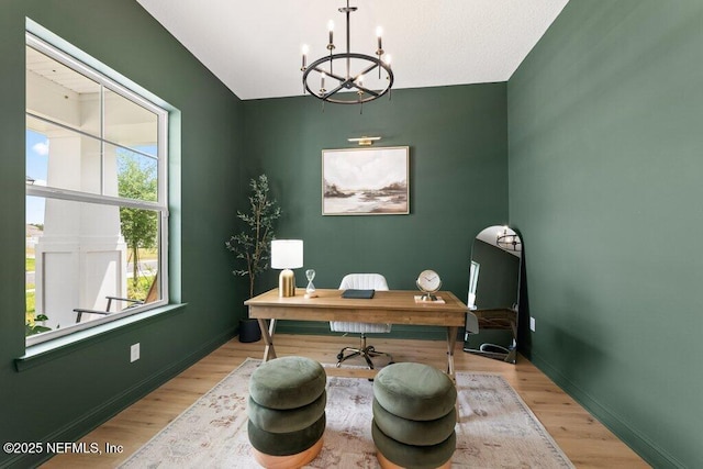 office space featuring light wood finished floors, a notable chandelier, and baseboards