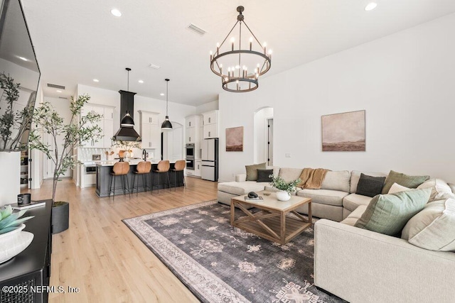 living area featuring recessed lighting, arched walkways, light wood-style flooring, a chandelier, and visible vents