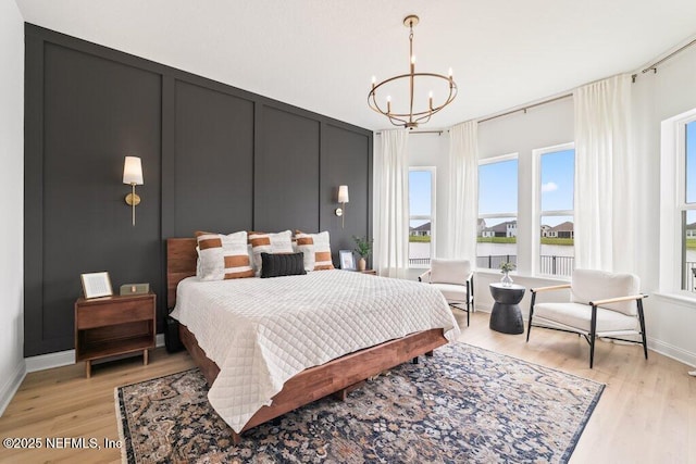 bedroom featuring a chandelier, light wood-type flooring, and baseboards