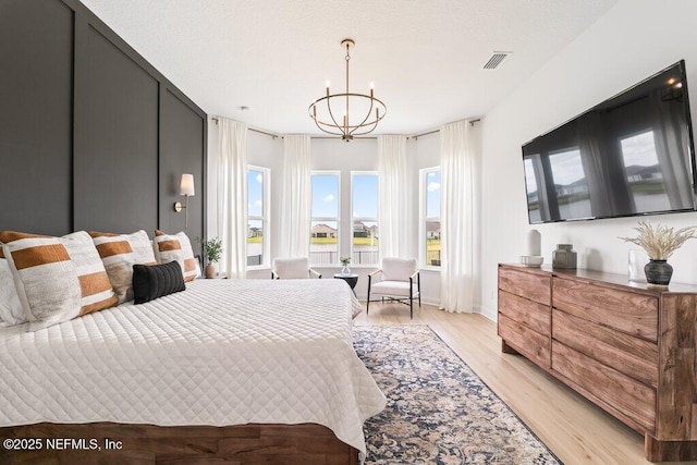 bedroom featuring visible vents, a chandelier, light wood-style flooring, and baseboards