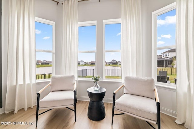 sitting room featuring baseboards, wood finished floors, a wealth of natural light, and a water view