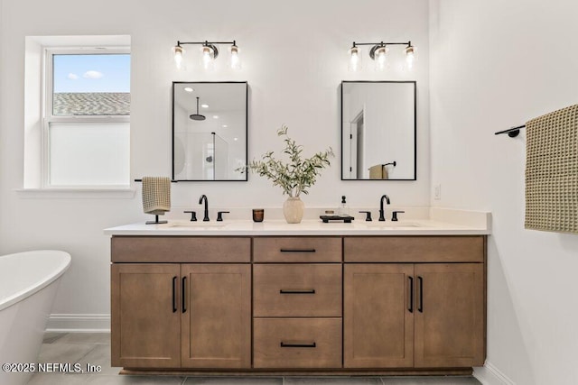 full bath featuring double vanity, baseboards, a freestanding tub, and a sink