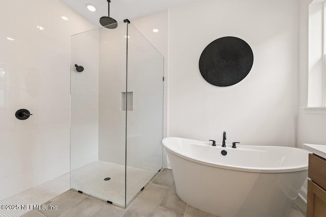 bathroom with tile patterned floors, vanity, a walk in shower, and a soaking tub