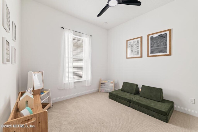 living area featuring baseboards, a ceiling fan, and carpet