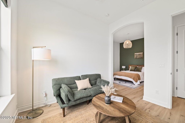 living room with light wood finished floors, arched walkways, and baseboards
