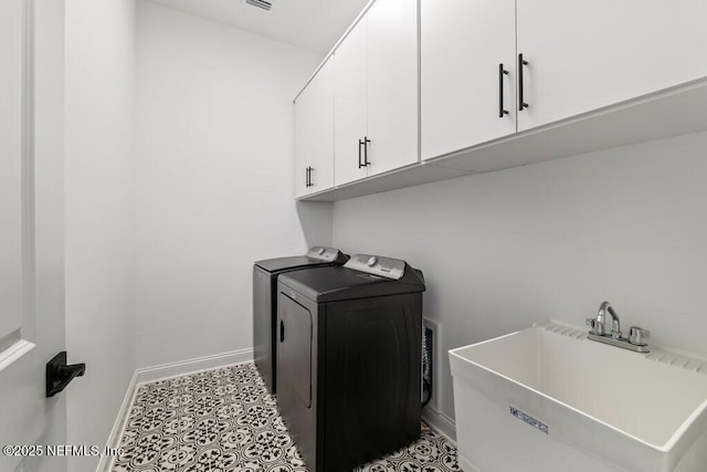 clothes washing area with baseboards, washer and dryer, cabinet space, and a sink