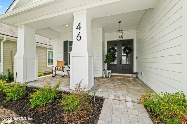 property entrance featuring covered porch and french doors