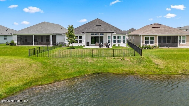 rear view of house with a sunroom, a yard, a water view, and a fenced backyard