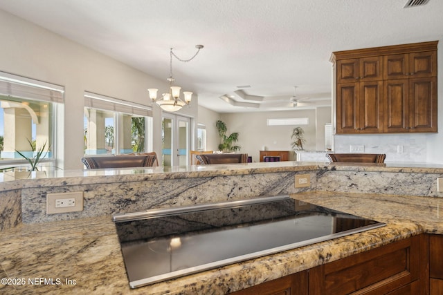 132 Beachside Dr, Ponte Vedra Beach, FL 32082 - kitchen featuring a tray ceiling, a chandelier, light stone countertops, black electric stovetop, and decorative light fixtures