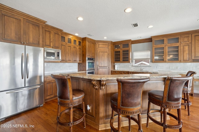 132 Beachside Dr, Ponte Vedra Beach, FL 32082 - kitchen with visible vents, light stone countertops, brown cabinets, and appliances with stainless steel finishes