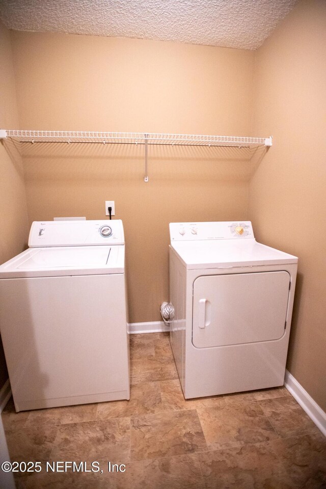 laundry area featuring baseboards, washer and dryer, laundry area, and a textured ceiling