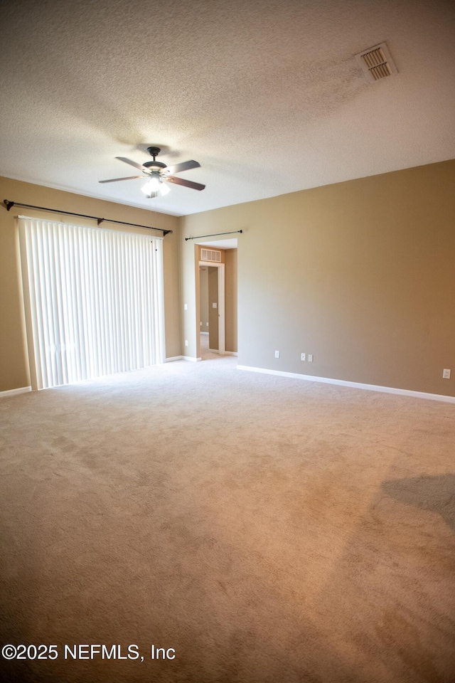 unfurnished room with visible vents, a textured ceiling, light colored carpet, and ceiling fan