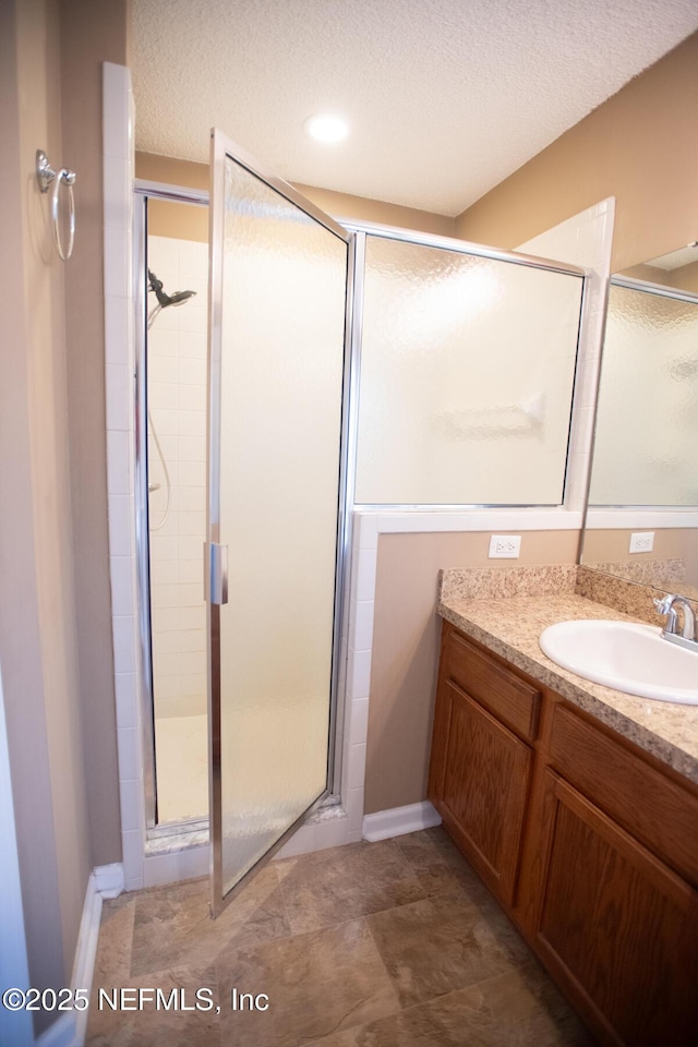 bathroom with a shower stall, vanity, and a textured ceiling