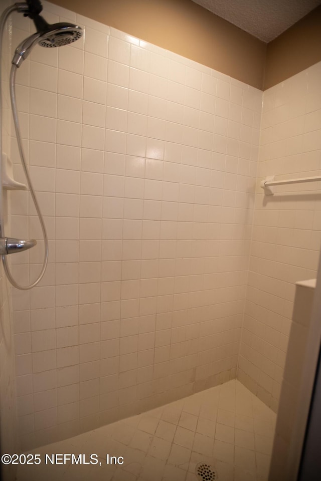 bathroom featuring a textured ceiling and a tile shower