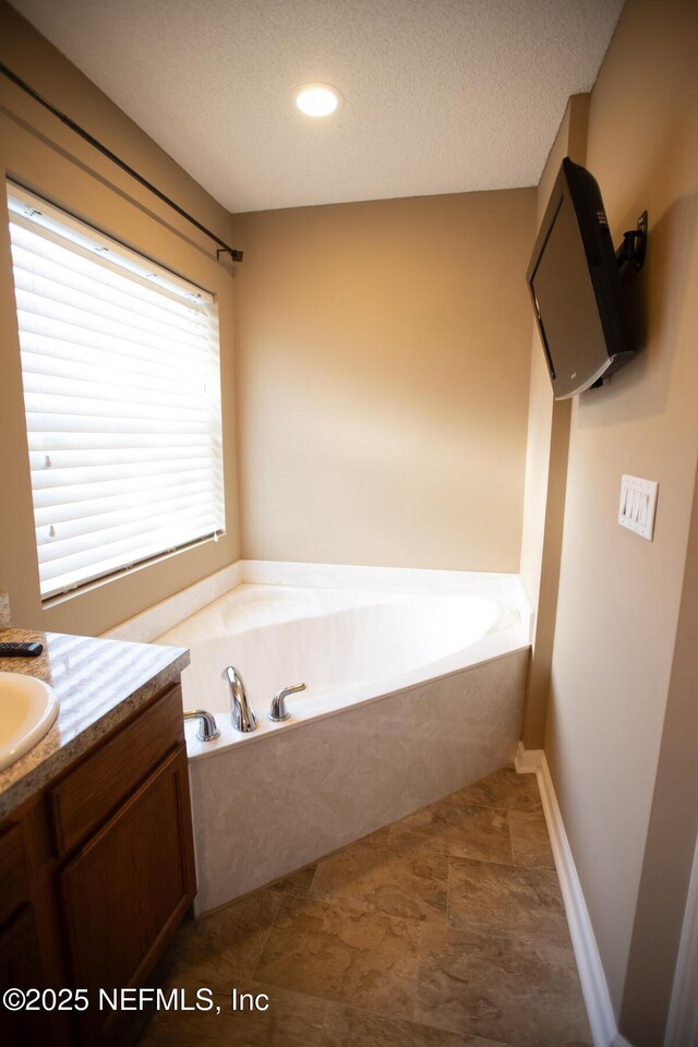 full bathroom with a textured ceiling, a garden tub, vanity, and recessed lighting