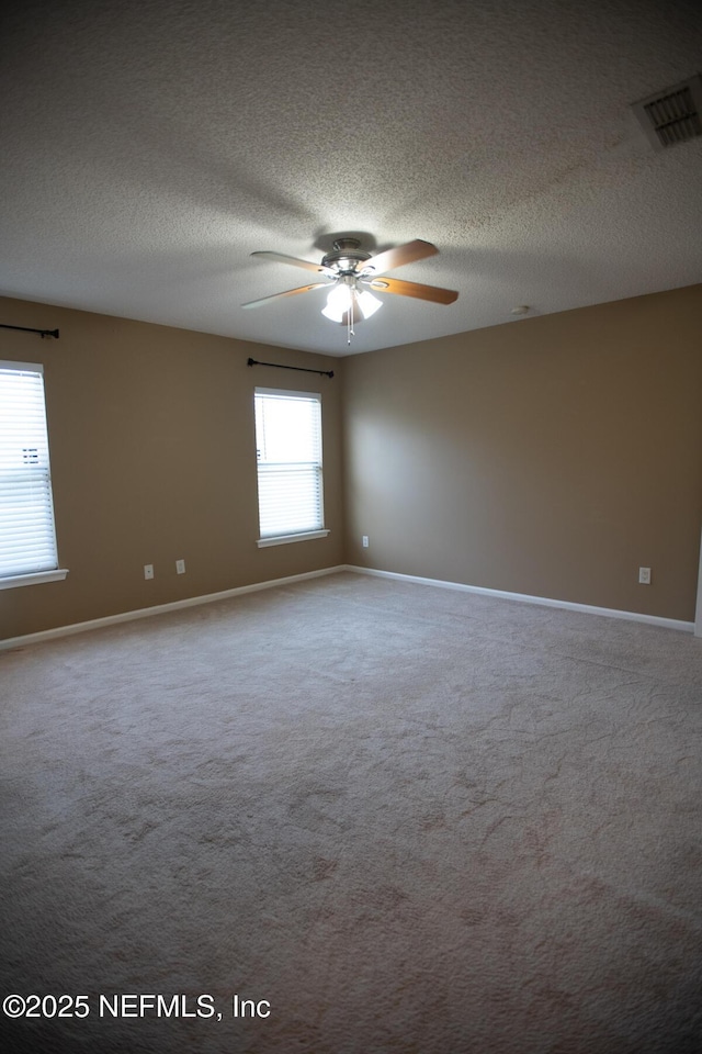 carpeted spare room with baseboards, visible vents, a textured ceiling, and a ceiling fan