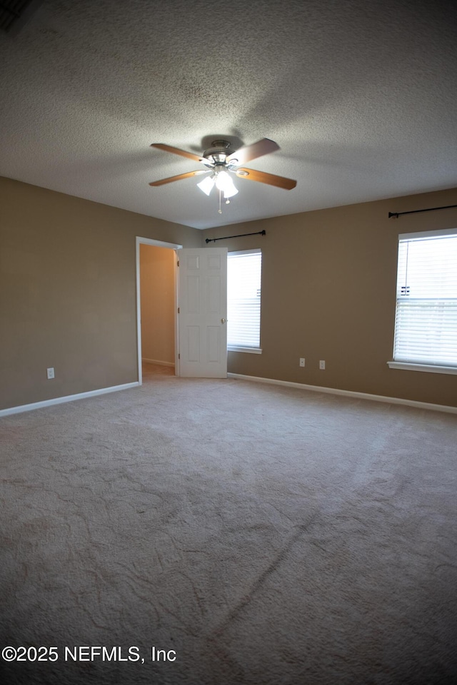 carpeted spare room featuring baseboards, a ceiling fan, and a healthy amount of sunlight