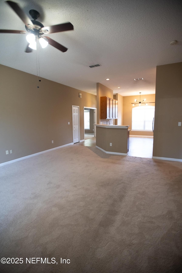 unfurnished living room with a textured ceiling, a ceiling fan, visible vents, light carpet, and baseboards