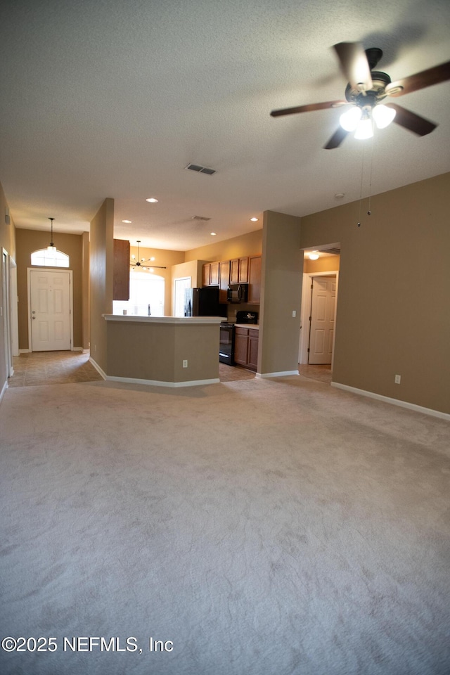 unfurnished living room with ceiling fan with notable chandelier, a textured ceiling, light colored carpet, visible vents, and baseboards