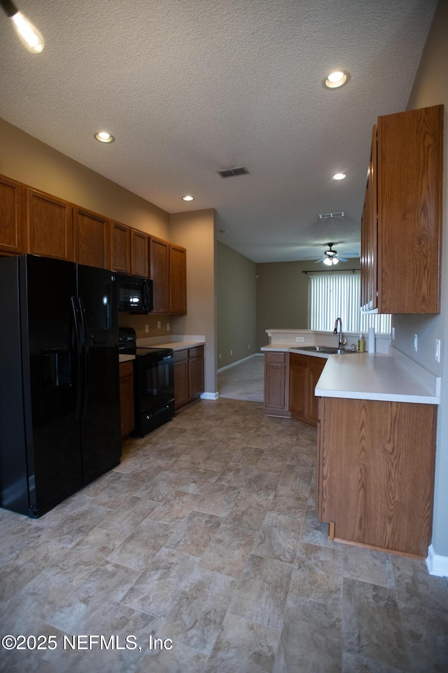 kitchen with a peninsula, visible vents, brown cabinets, and black appliances