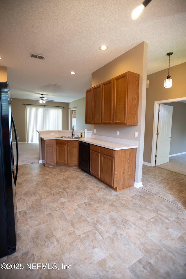 kitchen with a peninsula, visible vents, black appliances, light countertops, and brown cabinets