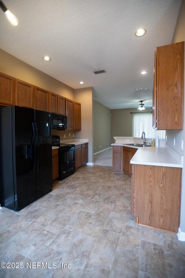 kitchen featuring brown cabinets, visible vents, black appliances, and a peninsula