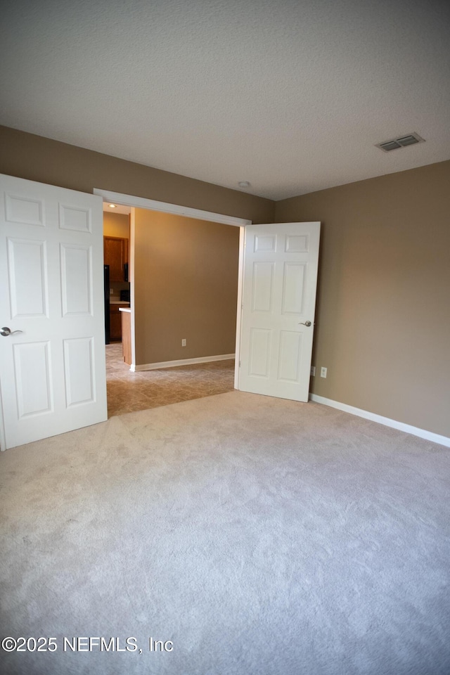 unfurnished bedroom featuring carpet flooring, visible vents, baseboards, and a textured ceiling