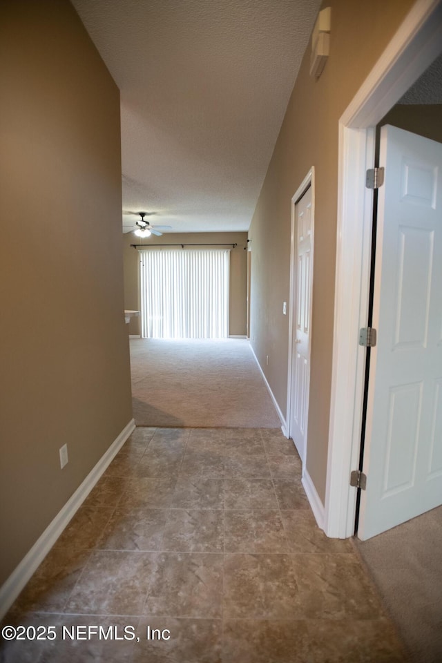 hall with baseboards and carpet flooring