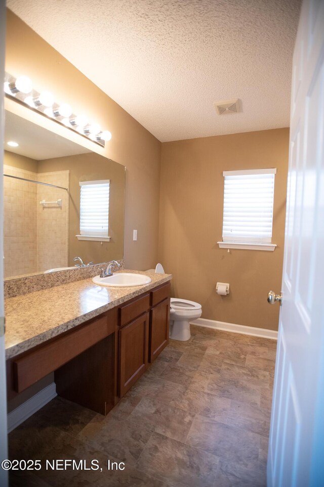 full bath with vanity, baseboards, a textured ceiling, toilet, and visible vents