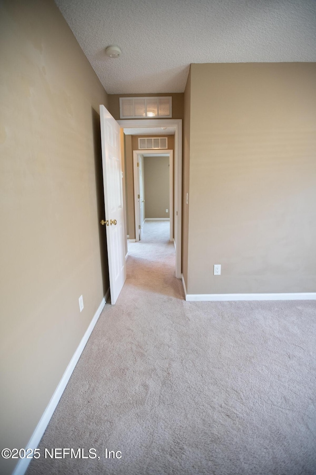 empty room with visible vents, baseboards, carpet, and a textured ceiling