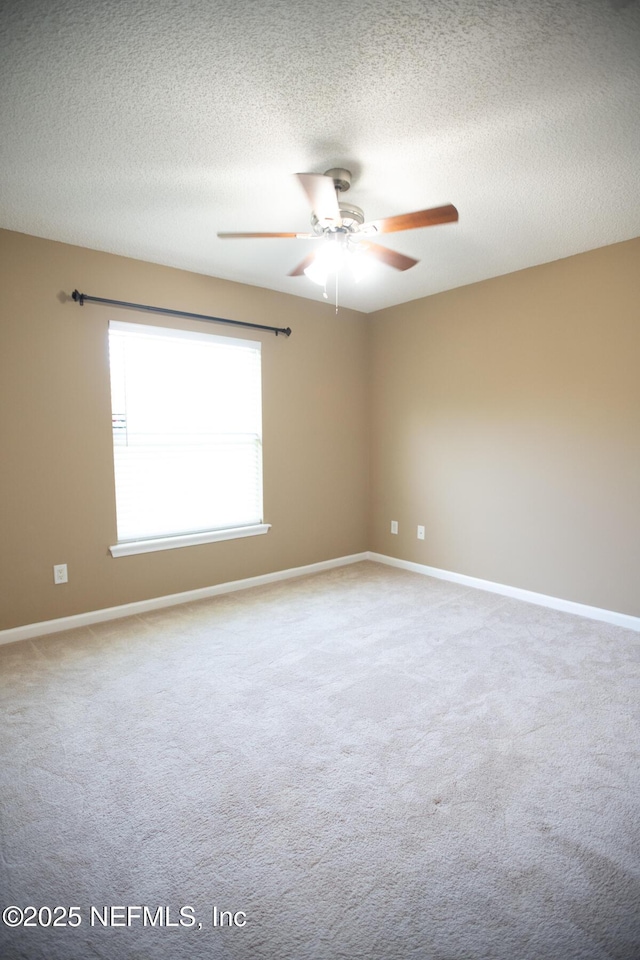 empty room featuring a textured ceiling, baseboards, a ceiling fan, and carpet