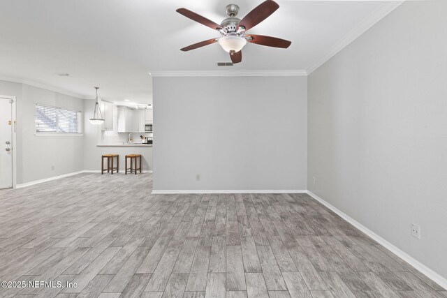 unfurnished living room with a ceiling fan, baseboards, ornamental molding, and light wood-style flooring