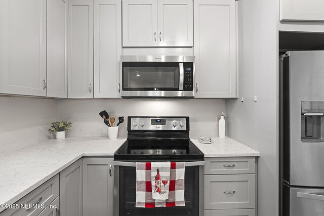 kitchen featuring appliances with stainless steel finishes, gray cabinets, and light stone counters