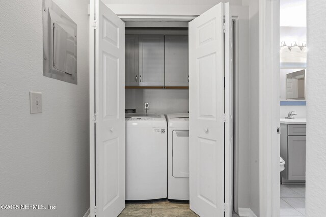 laundry area featuring separate washer and dryer, a sink, cabinet space, and electric panel