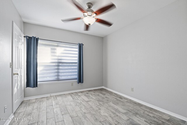 spare room featuring baseboards, ceiling fan, and wood finished floors
