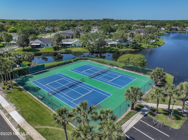 view of sport court featuring a residential view, fence, and a water view