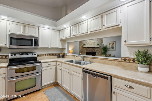 96033 River Marsh Bnd, Fernandina Beach, FL 32034 - kitchen featuring stainless steel appliances, a sink, light countertops, light wood finished floors, and a stone fireplace